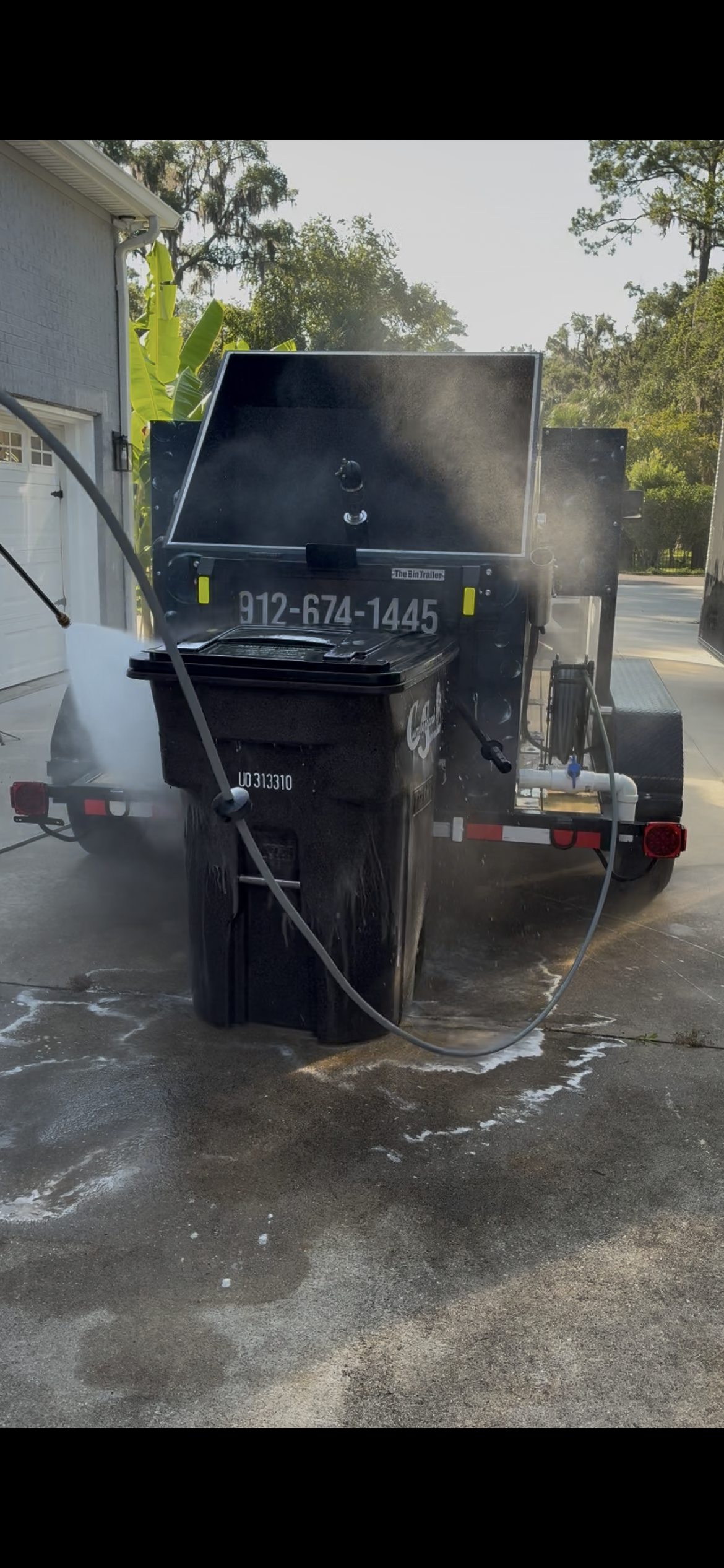 Harbor Bin Care trailer performing curbside bin cleaning at a home