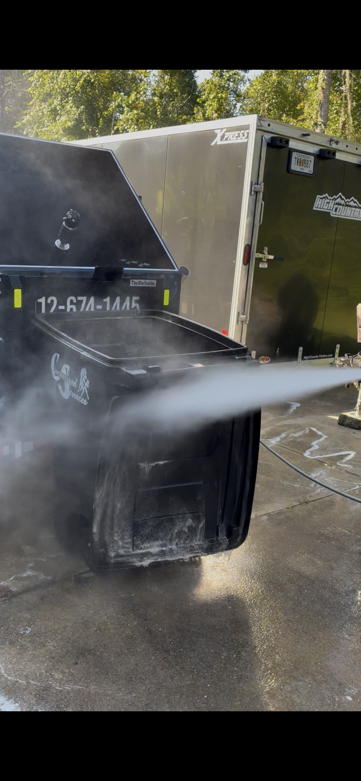 High pressure hot water blasting a trash bin clean